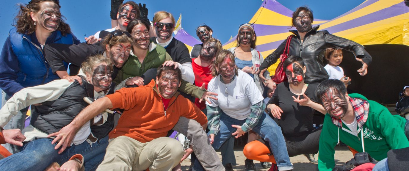 Photo of a group of people outside posing together with faces painted.