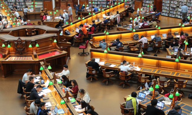 Aerial view of a library with rows of long study tables full of people.