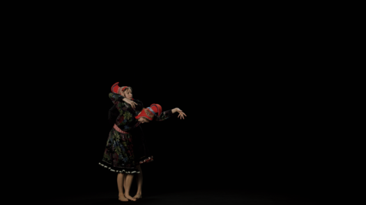Video still image of two performers in movement next to each other wearing traditional Sámi gákti against a black background.
